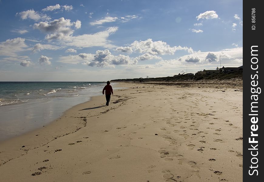 A boy walks along a secluded beach. A boy walks along a secluded beach