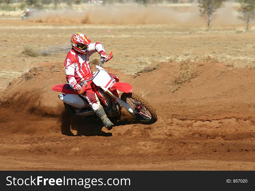 A motorbike races around the bend while a competitor races to catch up in the background, kicking up dirt along the way. Removed all logos and numbers for commercial use. A motorbike races around the bend while a competitor races to catch up in the background, kicking up dirt along the way. Removed all logos and numbers for commercial use.