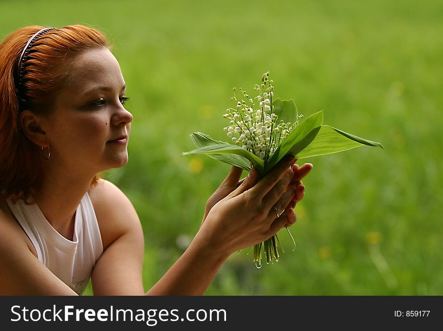 The girl with a bouquet of lilies of a valley on a green background. The girl with a bouquet of lilies of a valley on a green background