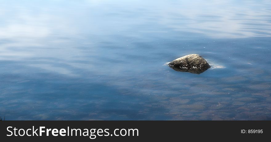 Lone rock in water.