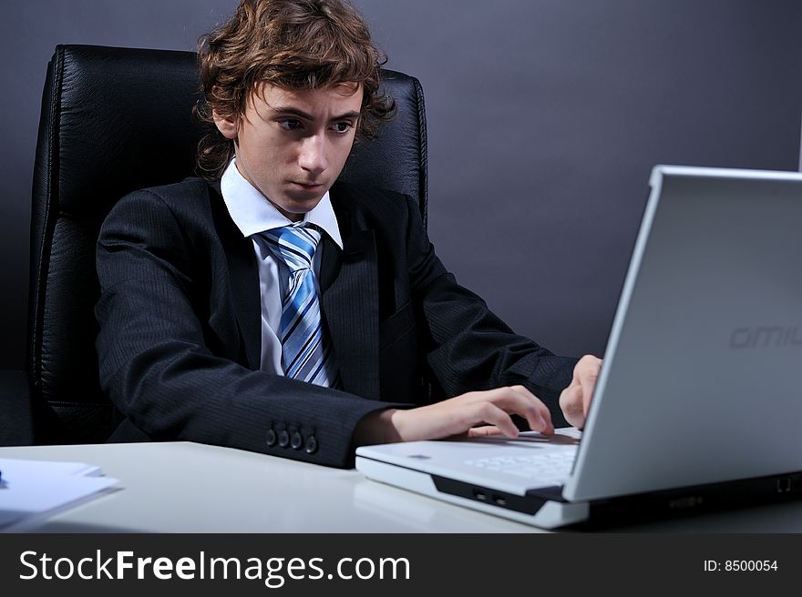 Young businessman at desk using computer laptop. Young businessman at desk using computer laptop