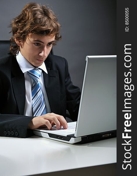 Young businessman at desk using computer laptop. Young businessman at desk using computer laptop