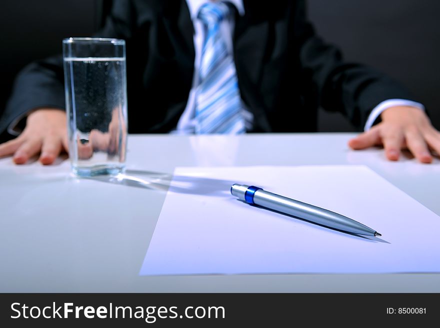 Desk detail with blank paper a pen and businessman hands. Desk detail with blank paper a pen and businessman hands