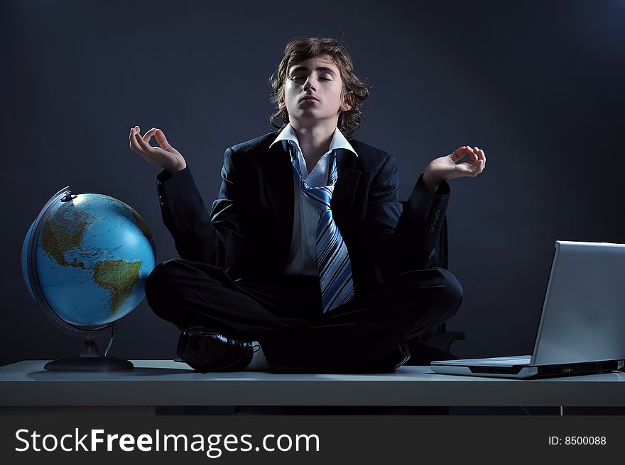 Businessman relaxing on desk in yoga lotus position