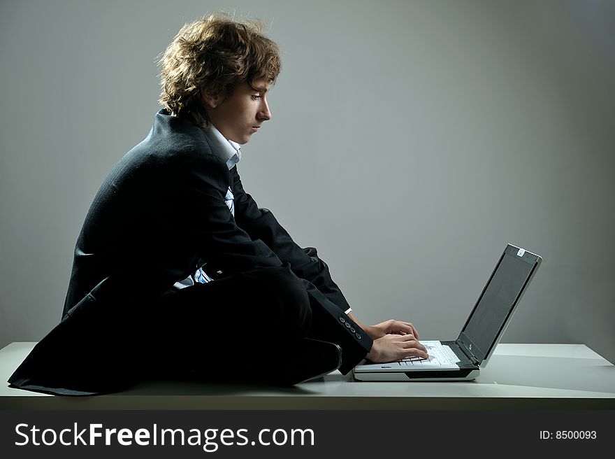 Businessman sitting on desk and using computer laptop. Businessman sitting on desk and using computer laptop