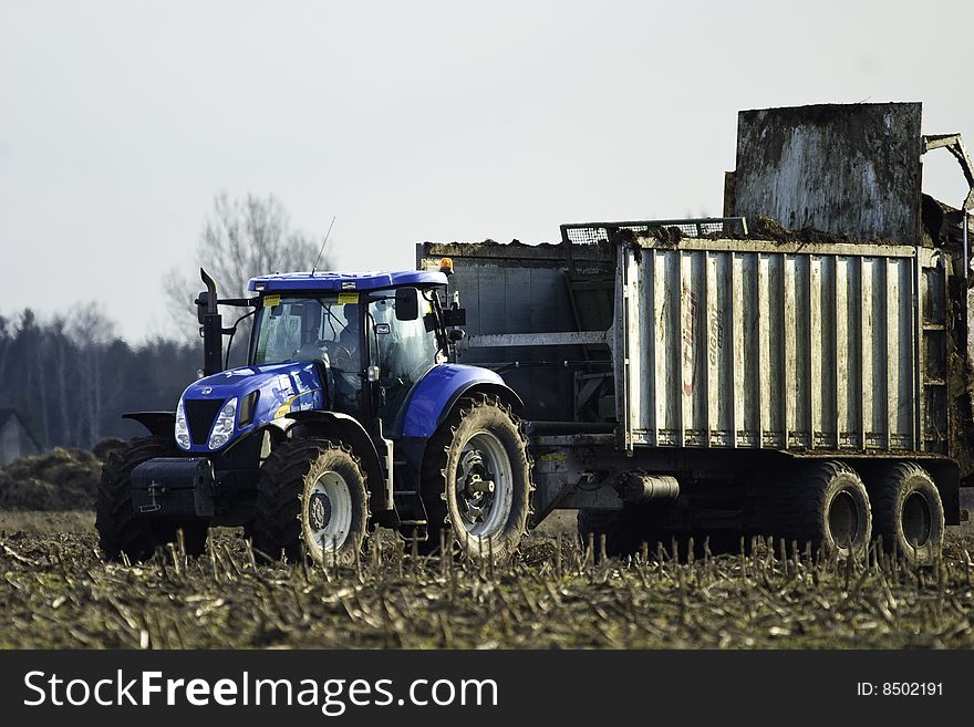 Blue big four wheel drive tractor working on field