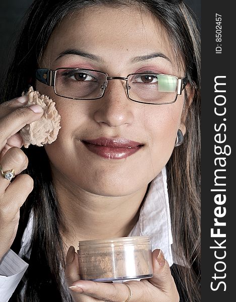 Girl applying makeup in studio.