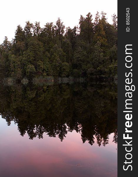 Reflection Of Trees On Lake At Sunset