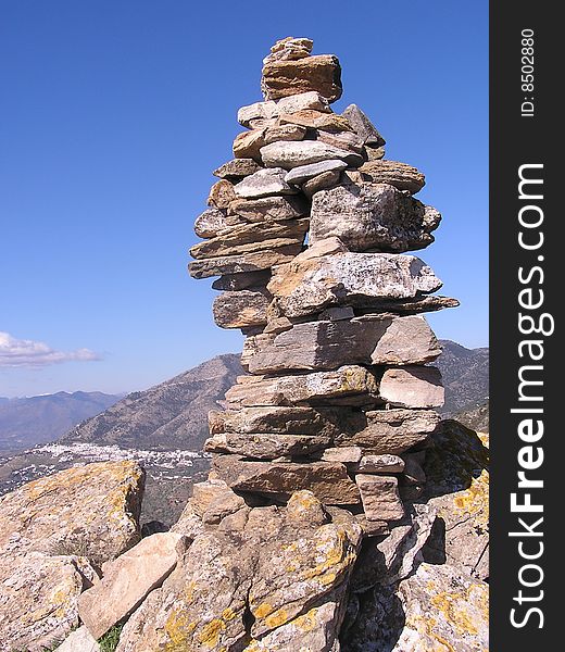 The summit cairn on Monte Mayor in Andalucia Spain outlined against a blue sky with Los Reales and a white village in the distance. The summit cairn on Monte Mayor in Andalucia Spain outlined against a blue sky with Los Reales and a white village in the distance.