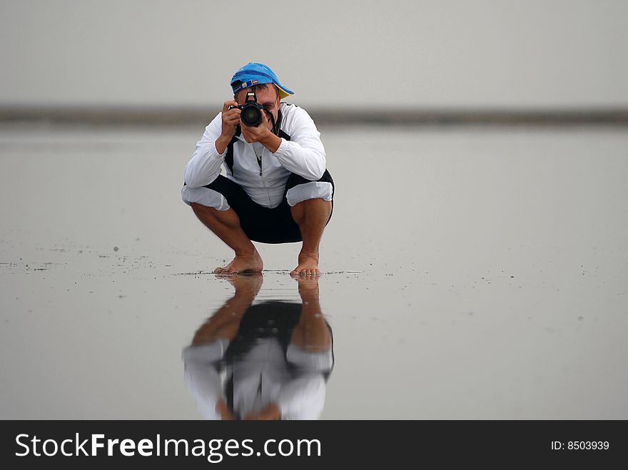 The young man photographing on hydrochloric lake in a sitting position. The young man photographing on hydrochloric lake in a sitting position