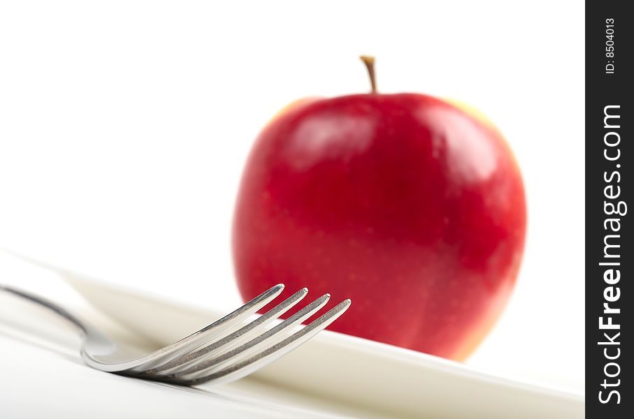 Utensils and red apple on white background