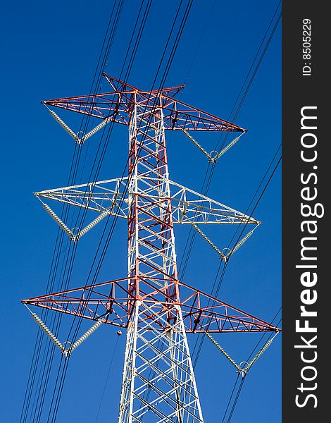 View from the bottom of a high voltage pylon in the background with the sky blue. View from the bottom of a high voltage pylon in the background with the sky blue