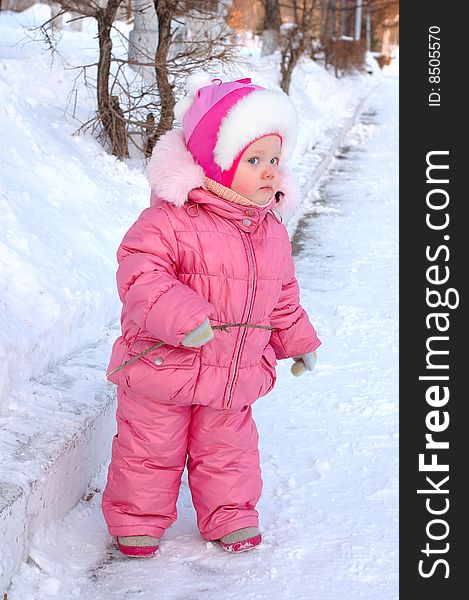 Pretty little girl in winter outerwear with branch on the snow. Pretty little girl in winter outerwear with branch on the snow.
