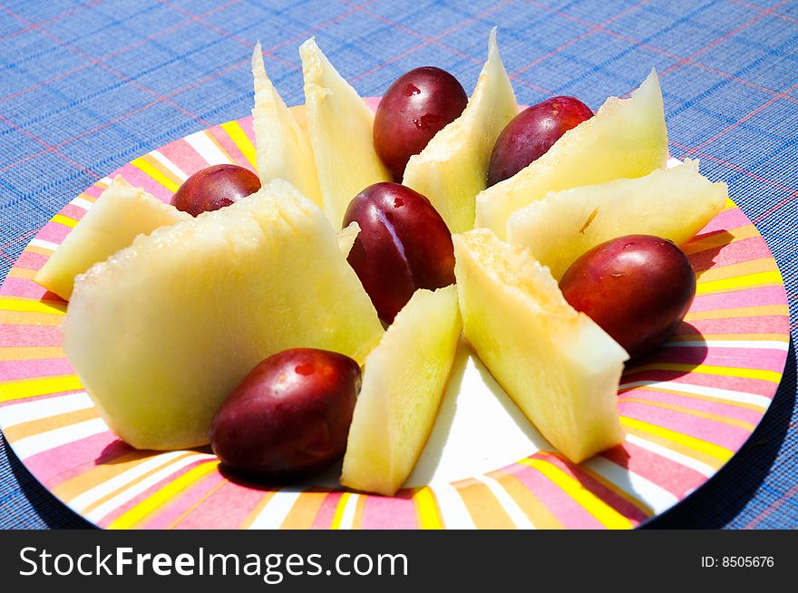 Closeup image of plums and melon on plate. Closeup image of plums and melon on plate