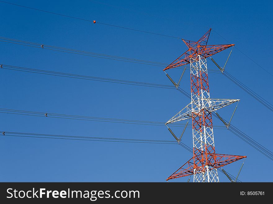 View from the bottom of a high voltage pylon in the background with the sky blue. View from the bottom of a high voltage pylon in the background with the sky blue