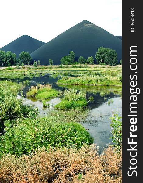 Marsh and the black mountains of slags in Kazakhstan, Asia