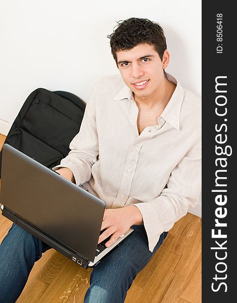 Happy young man working on his laptop with casual clothing and bag. Happy young man working on his laptop with casual clothing and bag