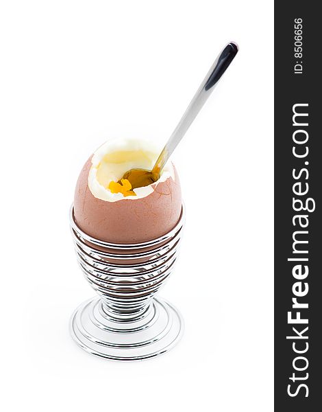 An eggcup with pealed egg and teaspoon in it.