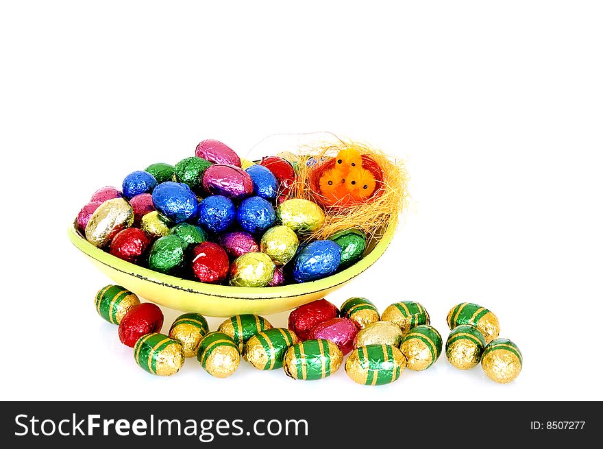 Bowl filled with colorfull wrapped chocolate easter eggs on white background, reflective surface. Bowl filled with colorfull wrapped chocolate easter eggs on white background, reflective surface