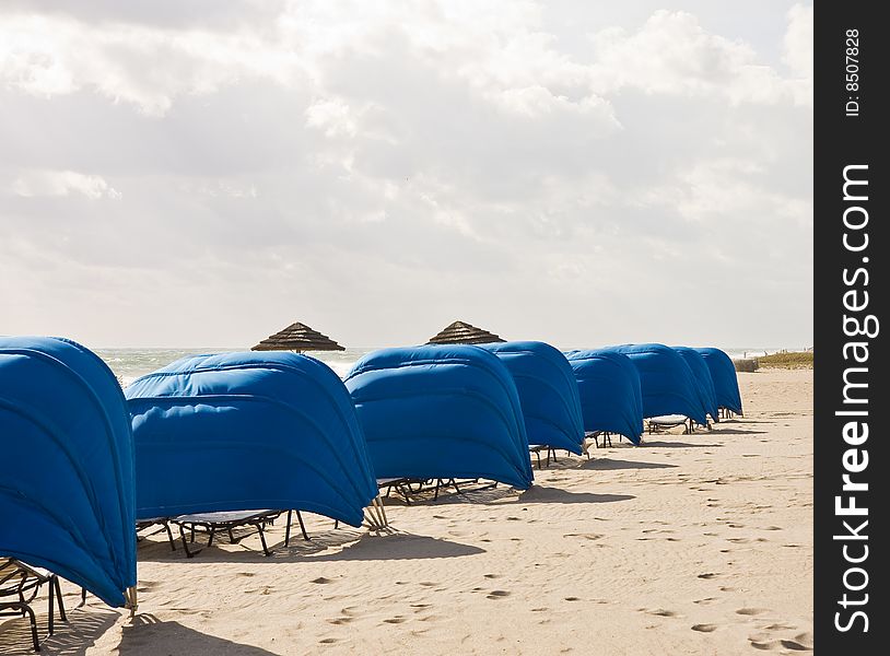 Blue Beach Shelters and Umbrellas on a beach on a cloudy day. Blue Beach Shelters and Umbrellas on a beach on a cloudy day