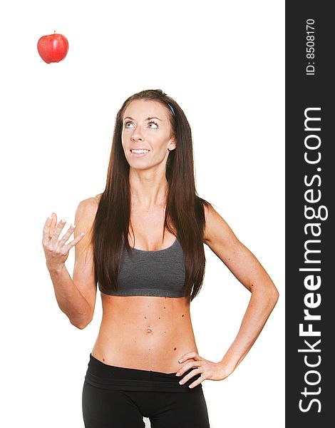 Fitness woman tossing up a red apple isolated on white