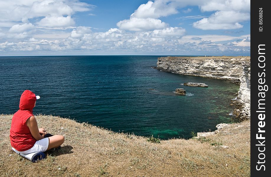 A woman is sitting near the sea bay. A woman is sitting near the sea bay