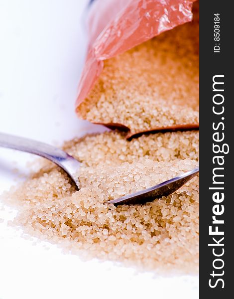 A mound of packaged brown sugar with a spoon. A mound of packaged brown sugar with a spoon