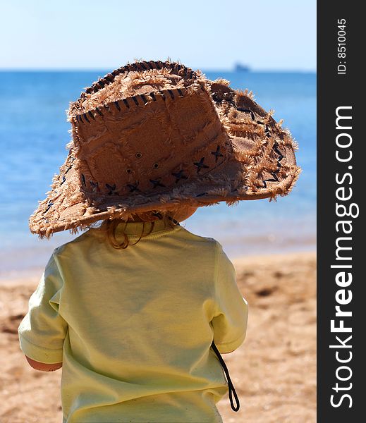 A little girl in a big cowboy hat on the beach. A little girl in a big cowboy hat on the beach