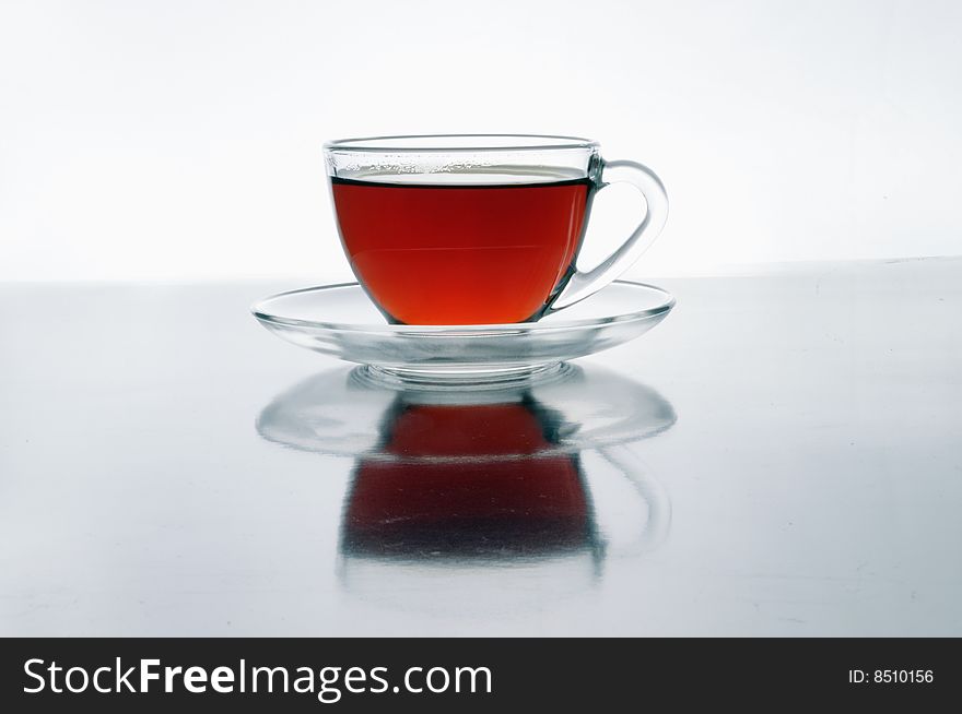 A glass cup of tea on black isolated on white background