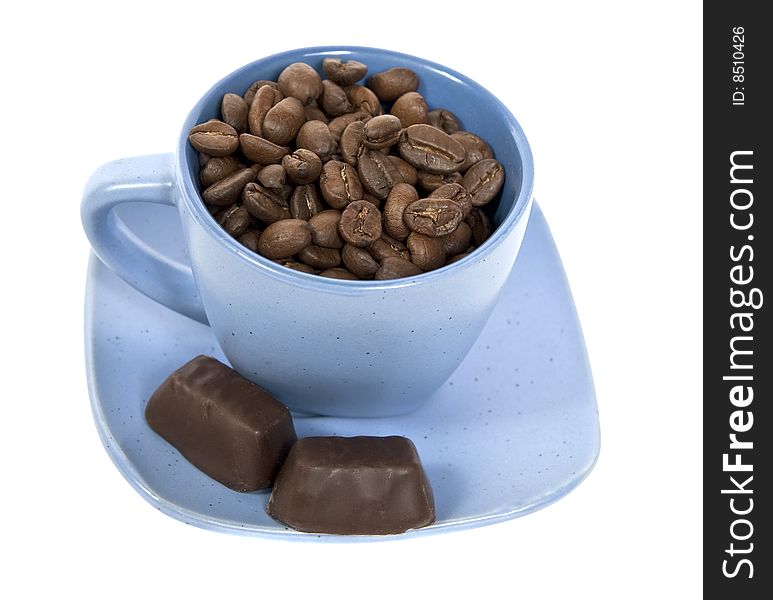 Cup with coffe beans and two chocolate candys