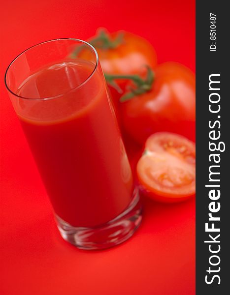 Fresh tomato juice and ripe tomatoes on a red background. Fresh tomato juice and ripe tomatoes on a red background