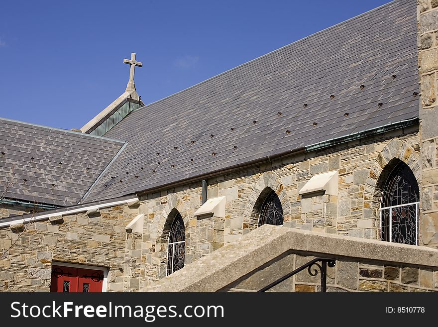 View from the side of a church showing the size of the building plus the cross on top, against a beautiful blue sky. View from the side of a church showing the size of the building plus the cross on top, against a beautiful blue sky