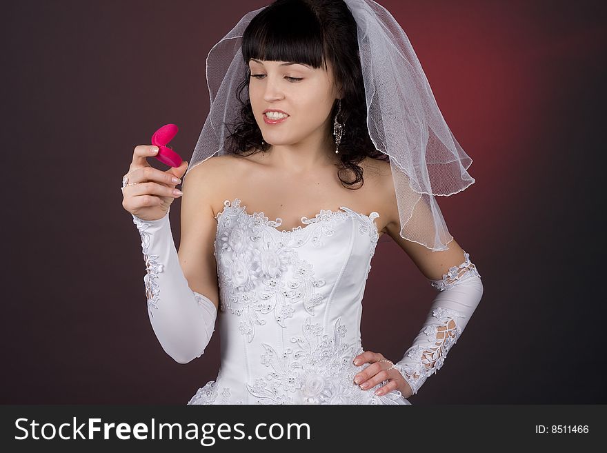 Beautiful young brunette bride looking at  wedding ring with smile. Beautiful young brunette bride looking at  wedding ring with smile