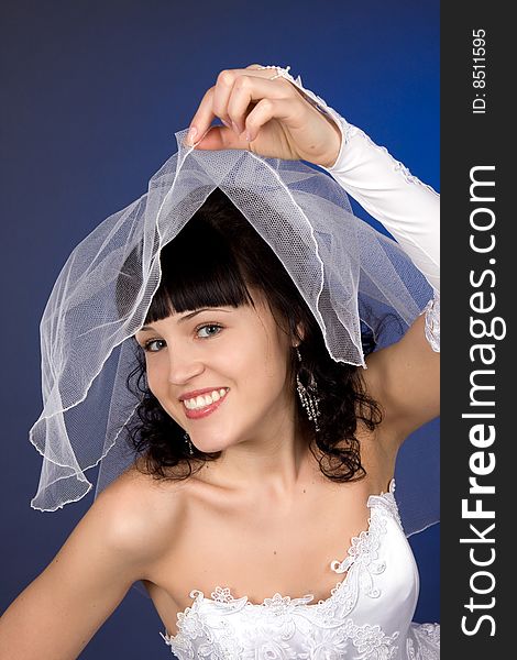 Studio portrait of a beautiful brunette bride against blue background