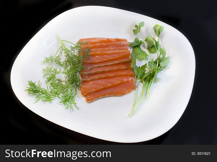 Salmon, fennel and parsley on a plate, a photo close up on a black background. Salmon, fennel and parsley on a plate, a photo close up on a black background.
