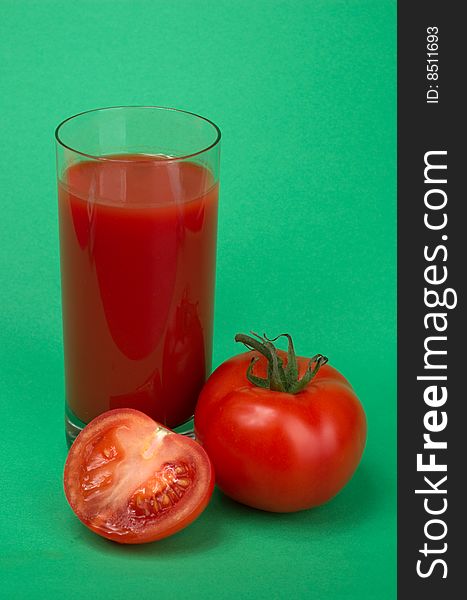 Tomatoes and fresh tomato juice on a green background. Tomatoes and fresh tomato juice on a green background