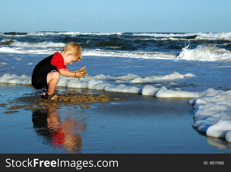 Boy playing in sand at water's edge. Boy playing in sand at water's edge