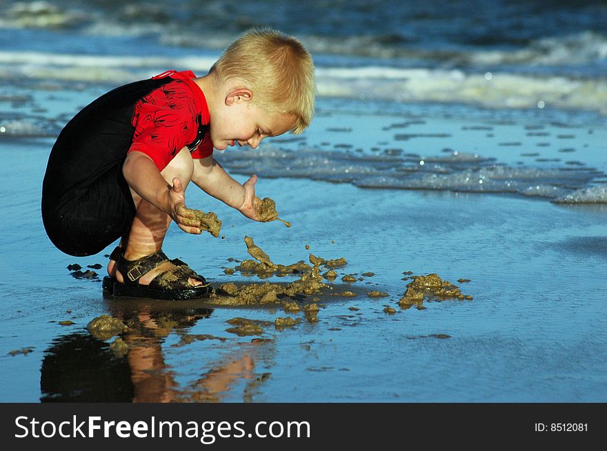 Boy playing in sand at water's edge