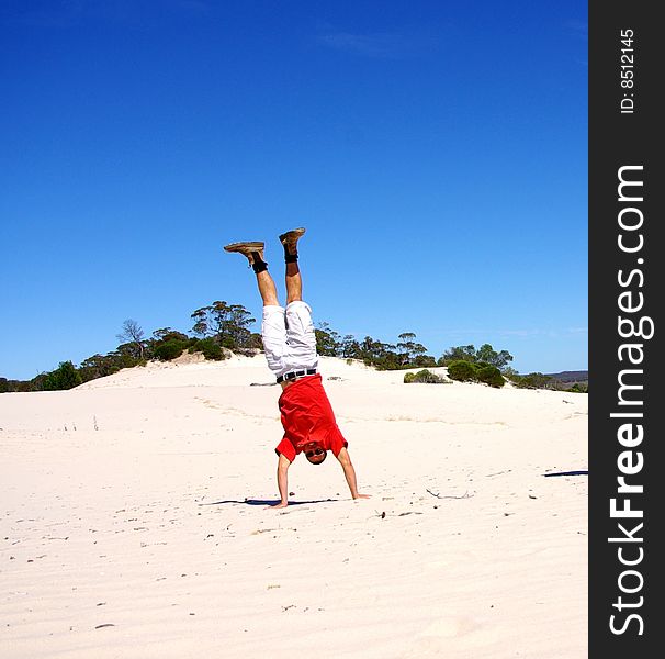 A man doing a handstand in Victoria's Mallee Desert at the 'Snowdrift' Sand Dune (Wyperfeld National Park, Australia). A man doing a handstand in Victoria's Mallee Desert at the 'Snowdrift' Sand Dune (Wyperfeld National Park, Australia).
