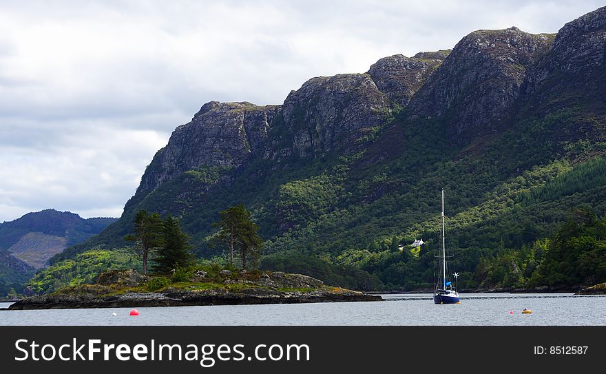 Sailboat upon loch carron with mountains and forest in the background. Scotland.