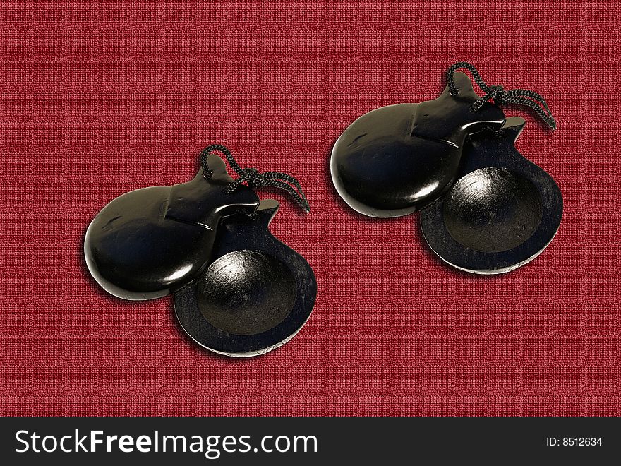 Two pair of castanets on the red textile background.