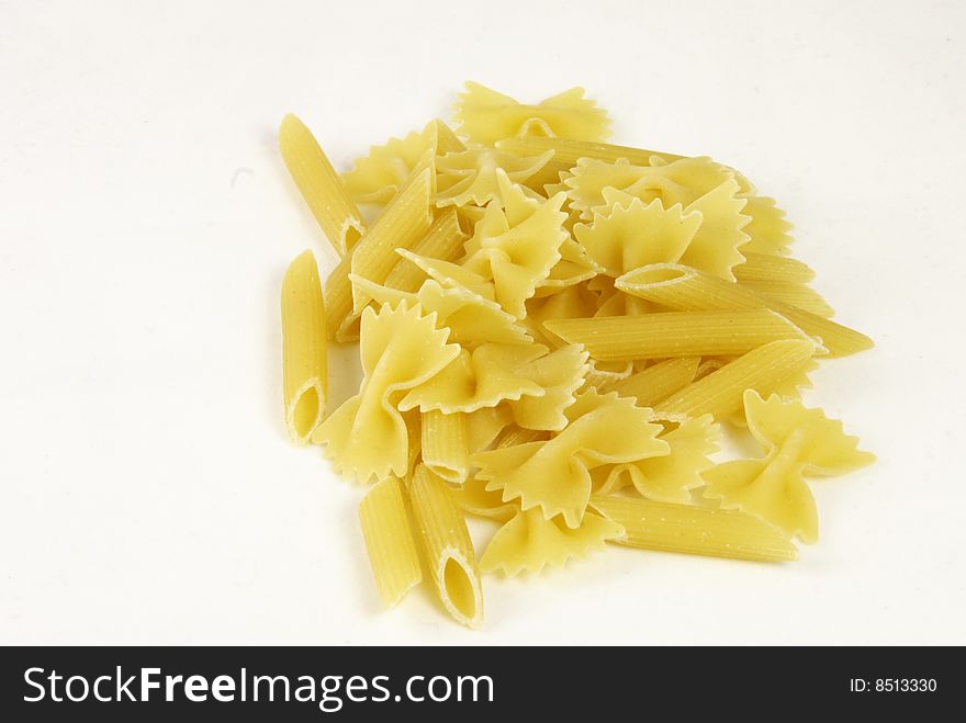 Pasta against a white background shaped as bows and tubes