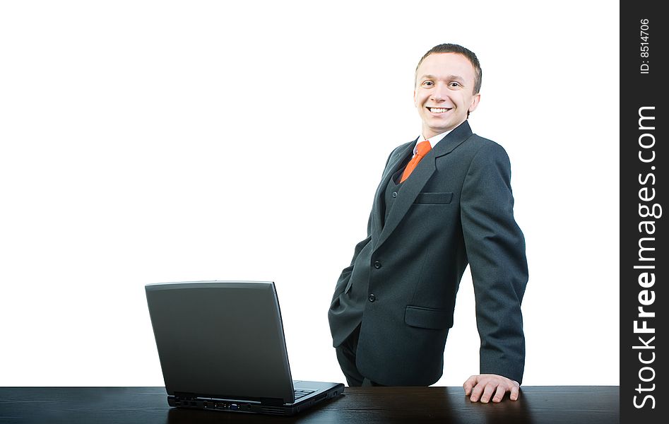 A young and happy businessman standing at a desk, propped up by hand. A young and happy businessman standing at a desk, propped up by hand.