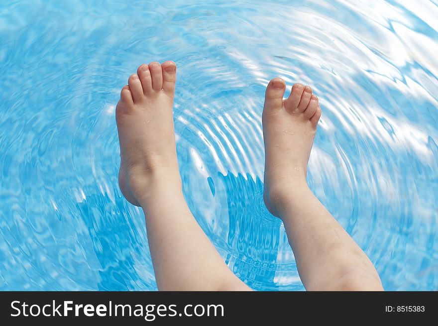 A young kids feet over blue pool water. A young kids feet over blue pool water