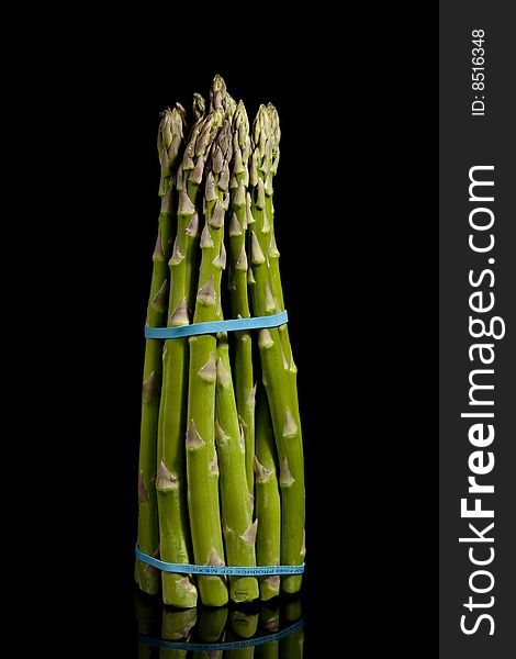 Full length view of asparagus on reflective surface and black background. Full length view of asparagus on reflective surface and black background