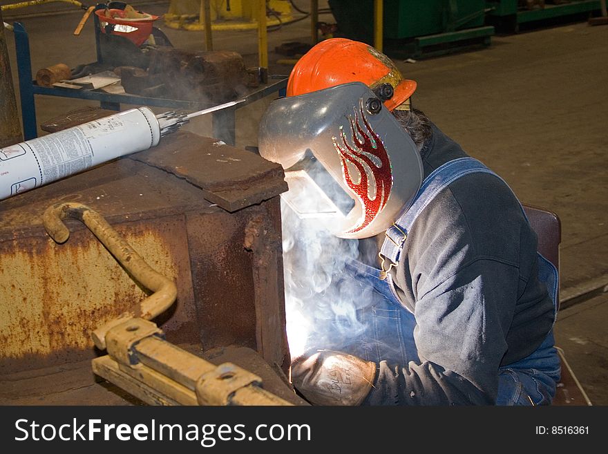 Man welding on railroad car with hard hat and welding shield. Man welding on railroad car with hard hat and welding shield.