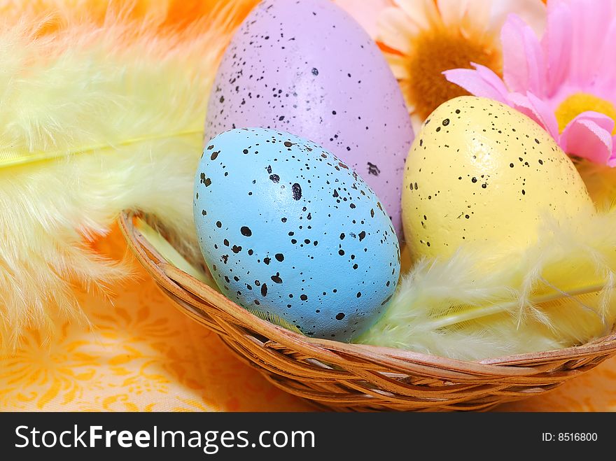 Three color eggs in the basket with soft yellow feathers making nice Easter composition. Three color eggs in the basket with soft yellow feathers making nice Easter composition.