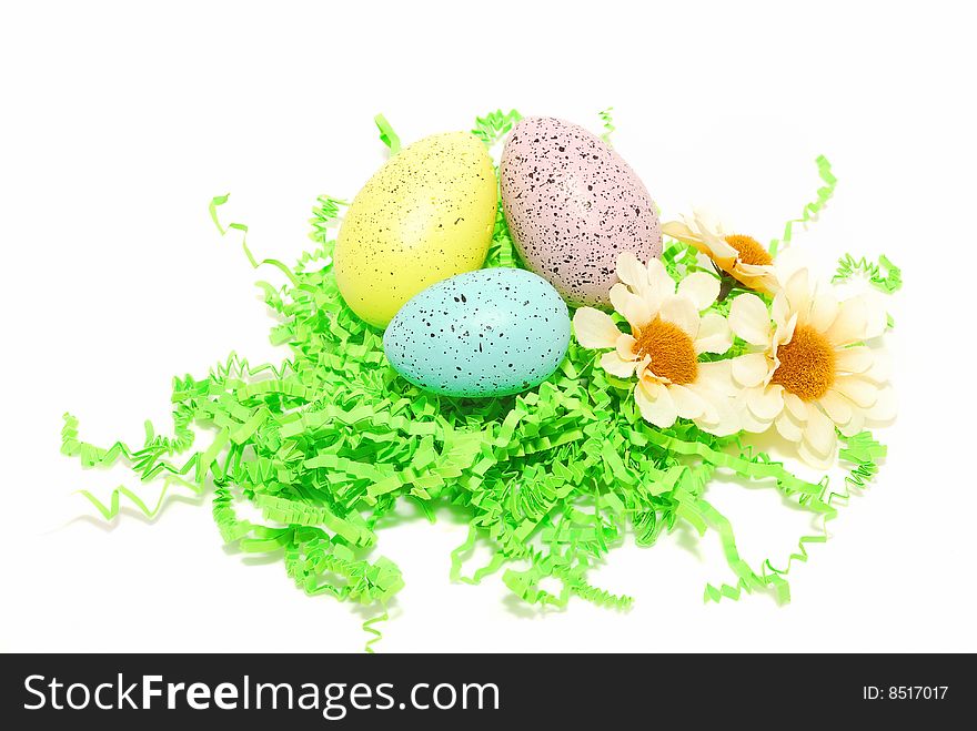 Easter eggs in green paper grass  with three flower isolated on the white. Easter eggs in green paper grass  with three flower isolated on the white