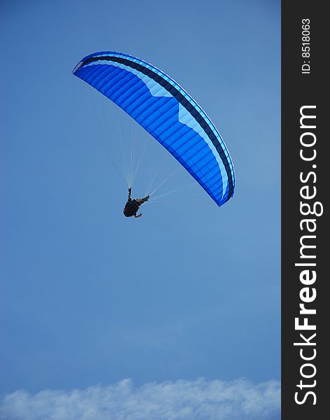 Blue wing over a pilot head doing paragliding activites. Blue wing over a pilot head doing paragliding activites