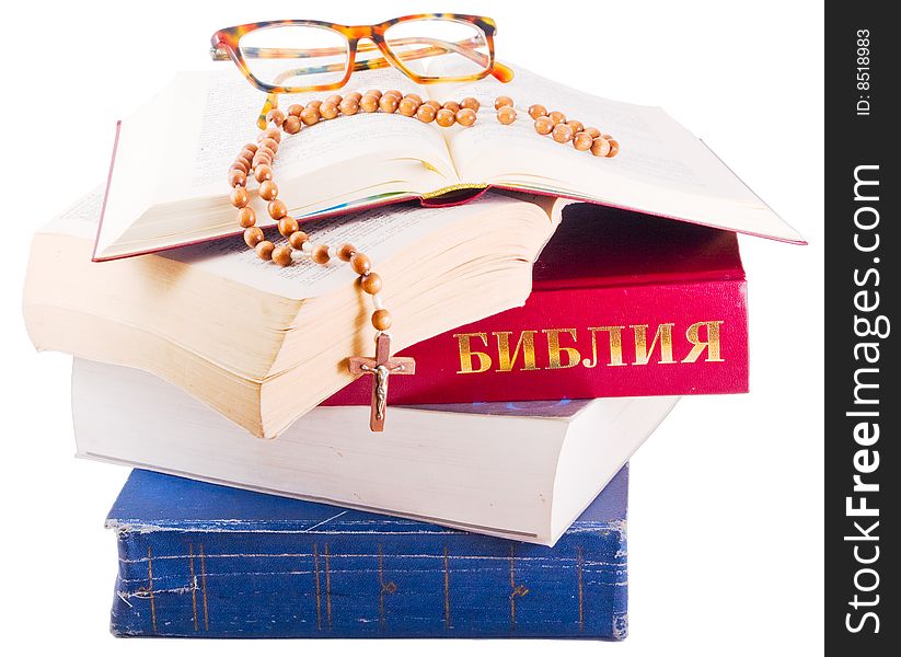 Open Holy Bible lying on stack of old books with glasses, cross and beads. Open Holy Bible lying on stack of old books with glasses, cross and beads